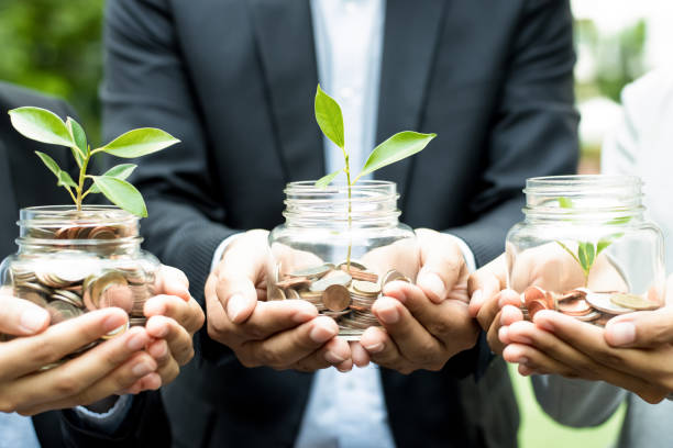 Getty Images - Three people holding a pot each with coin growing a plant.