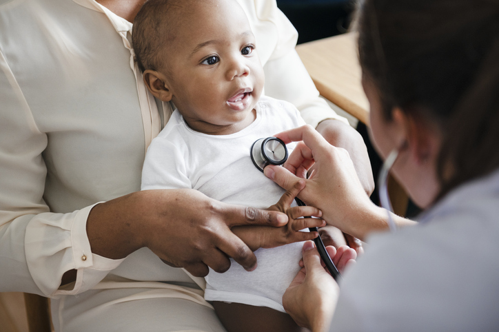 A doctor pressing a stethoscope to a baby's chest