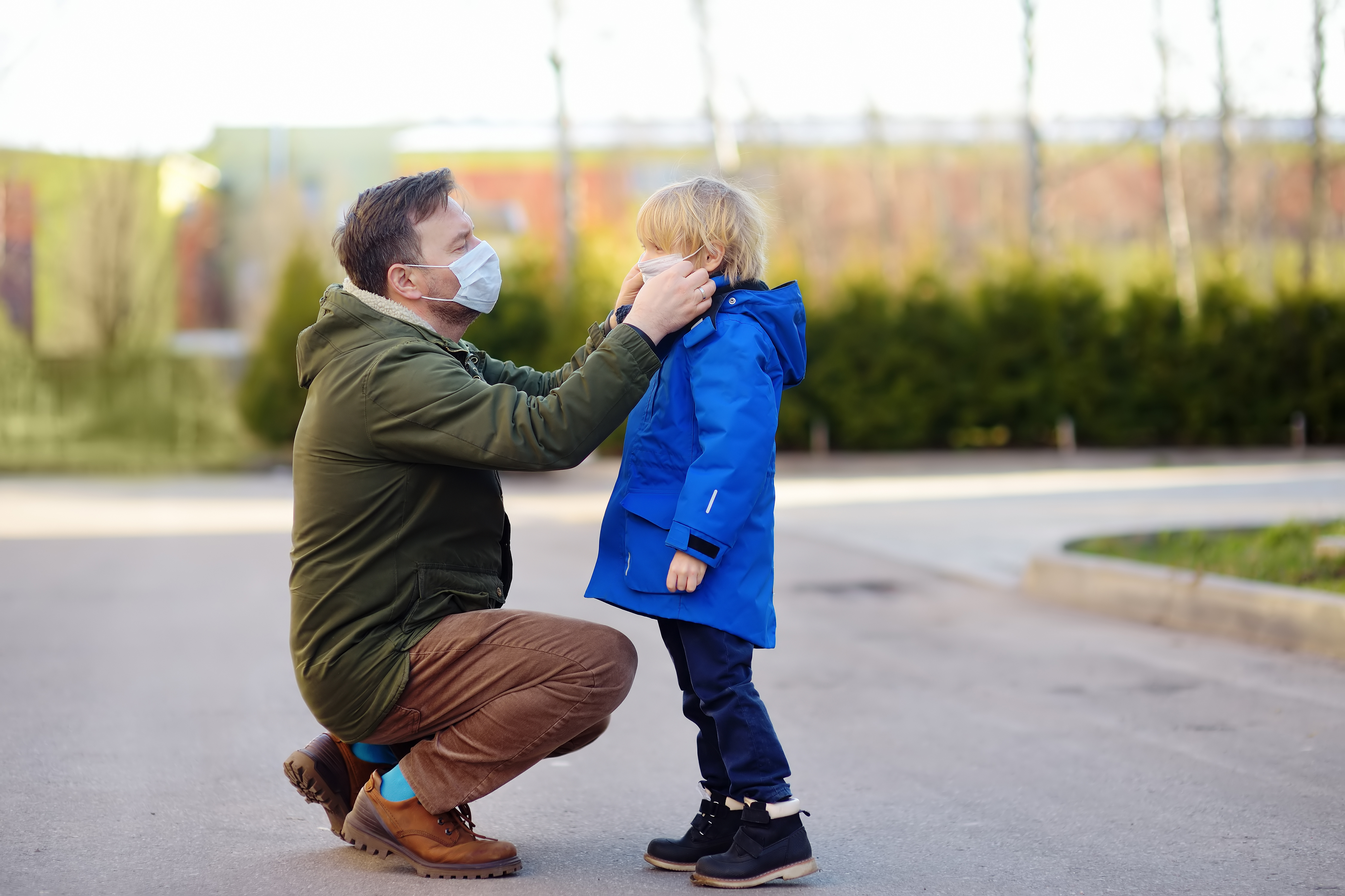 Father putting a protective face mask on his son.