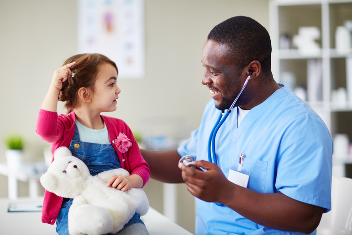 A young girl interacting with a healthcare worker, who is smiling and holding a stethoscope