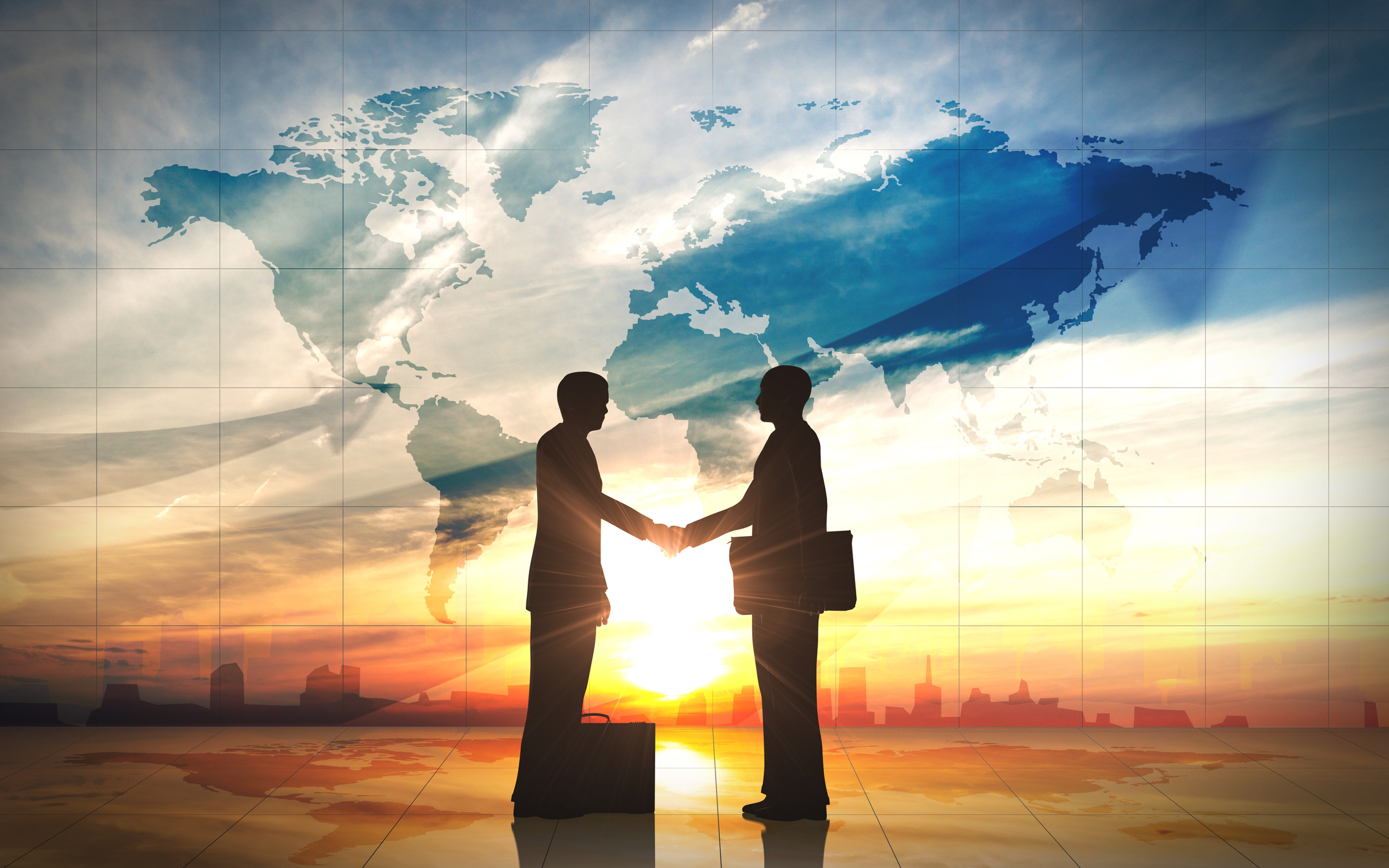 Global Business Elite Communities: Two people dressed in suits shaking hands against a world map