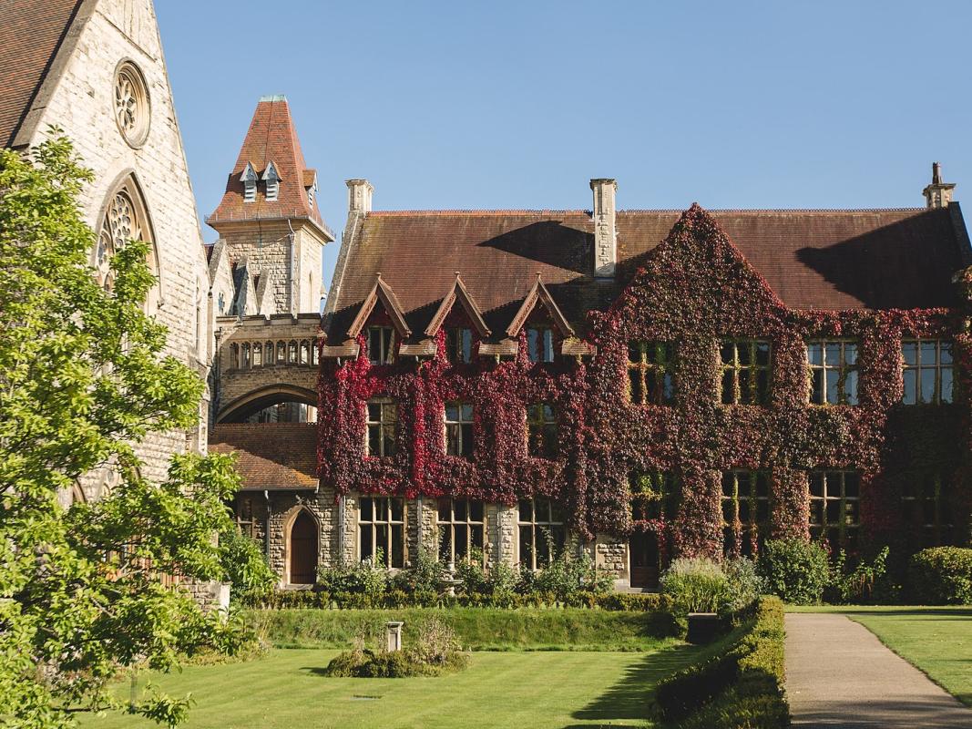 An ornate stone building in Cheltenham Ladies College, covered in ivy and with a lawn in front