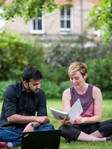 DSPI doctoral students in the Barnett House garden looking at a book together