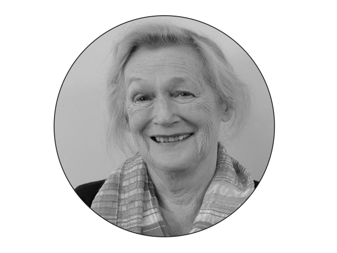 A black and white photo in a round photo frame of  Ann Buchanan wearing a suit smiling