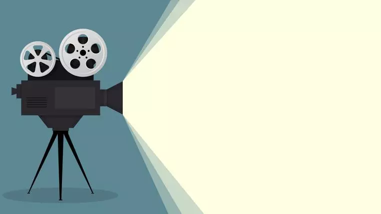 An illustration of an old-fashioned movie film camera, with film reels attached. A large ray of white light expands outwards from the camera lens.