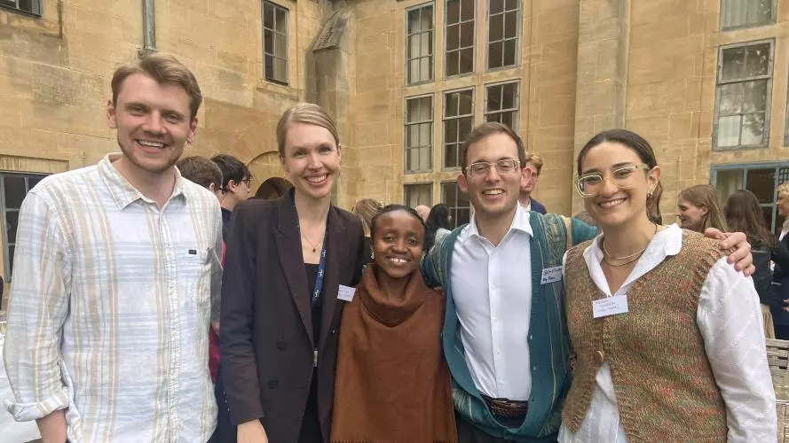 Two men and three women smiling with arms interlocked