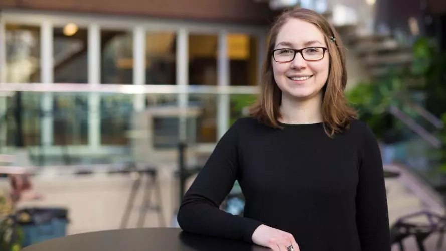 Mackenzie is a female wearing glasses and a black top with glasses