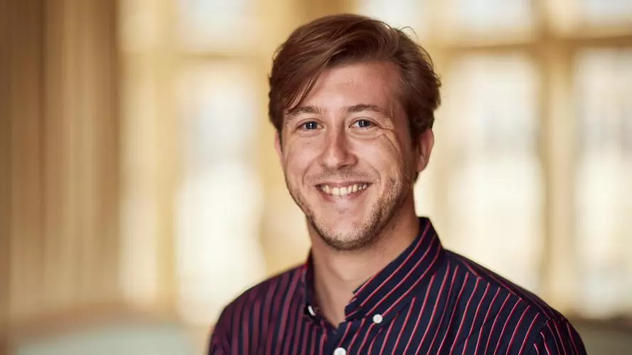 Dirk Witteveen has short hair, wearing a black and red striped shirt smiling at the camera.