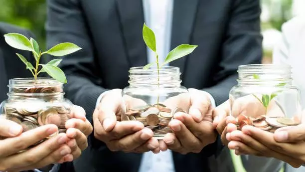 Getty Images - Three people holding a pot each with coin growing a plant.