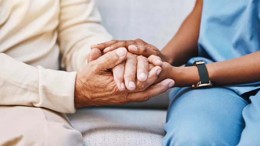 A close-up image of a nurse and a patient holding hands. Credit: Getty - PeopleImages 1473155461