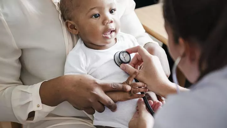 A doctor pressing a stethoscope to a baby's chest