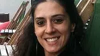 Ani has long black hair. She is wearing a black shirt and blazer
