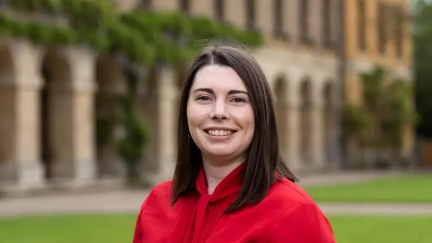 Dr Phillips has shoulder length brown hair, wearing a red, and she's top smiling at the camera. 