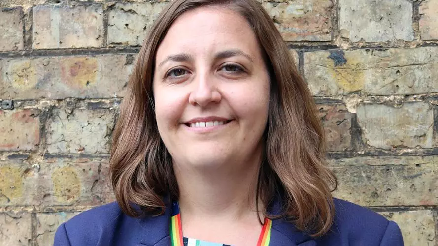 Woman with shoulder-length brown hair and brown eyes, smiling and wearing a dark blue jacket