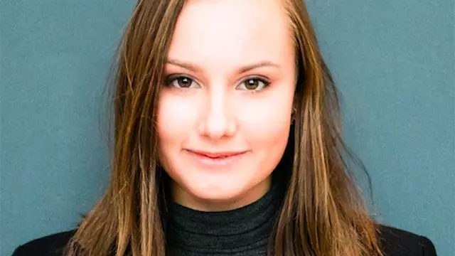 Michaela Bunakova has long brunette hair and is wearing a dark grey top and black blazer