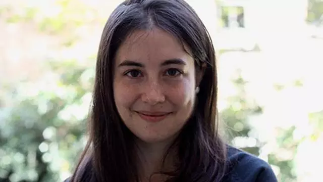 Paloma has long dark hair, is smiling at the camera and wearing a black top with navy blue jacket. 
