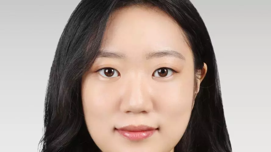 Solhee Han has long dark hair and is looking directly at the camera. She is wearing a white top and black jacket.