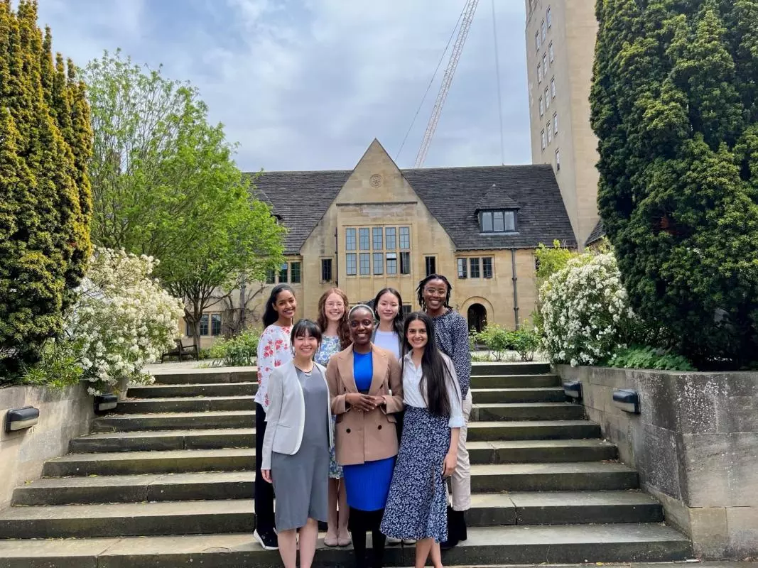A group of students standing on some steps in front of an Oxford college building