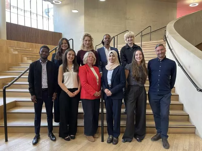 Two rows of smiling people standing on a sweeping stairway - 4 on the back row, six on the front row