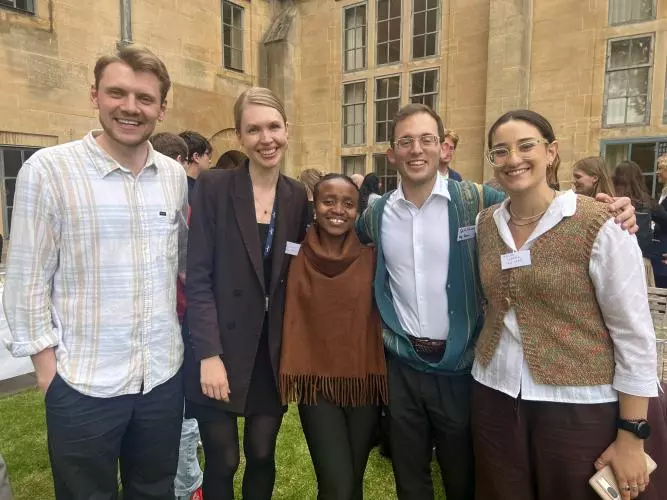 Two men and three women smiling with arms interlocked