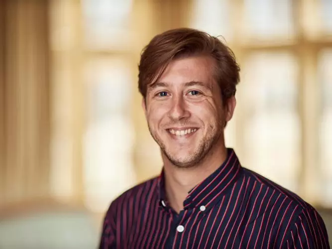 Dirk Witteveen has short hair, wearing a black and red striped shirt smiling at the camera.