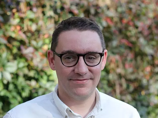 david humphries has short brown hair, glasses and wearing a white shirt.