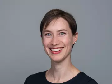 Inge Vallance has short dark hair and is smiling at the camera. She is wearing a black top.
