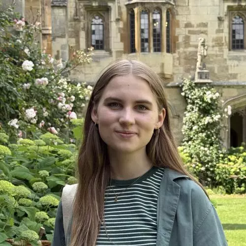 Liina stands in college grounds. She is wearing a striped tee-shirt and has long, fair hair.