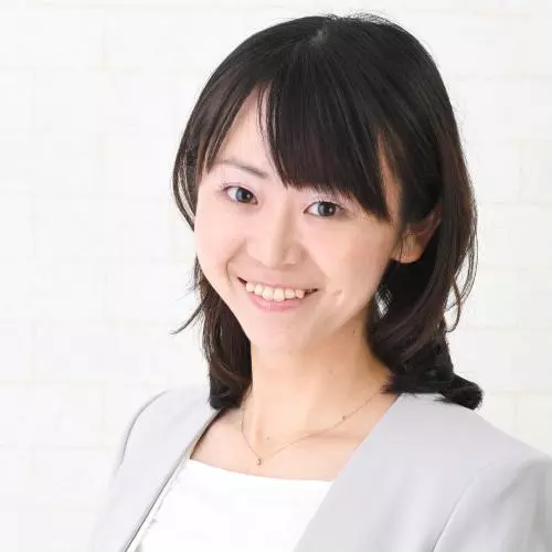 Aya has shoulder length black hair and a fringe. She's wearing a white top and pale grey jacket. 