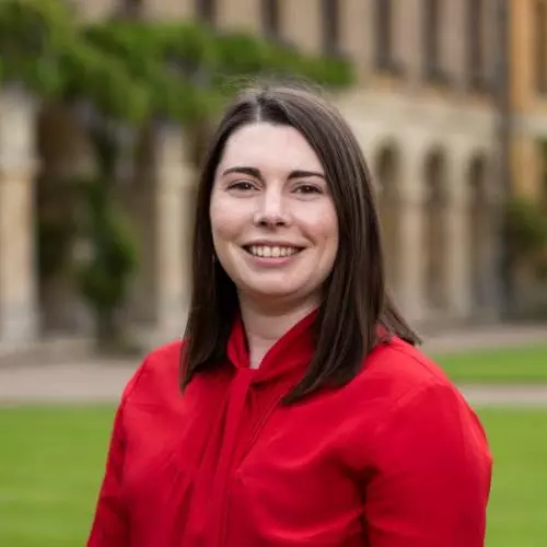 Dr Phillips has shoulder length brown hair, wearing a red, and she's top smiling at the camera. 