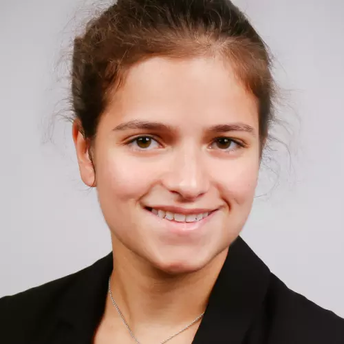 Woman who is smiling with brown hair tied back off her face and is wearing a black jacket