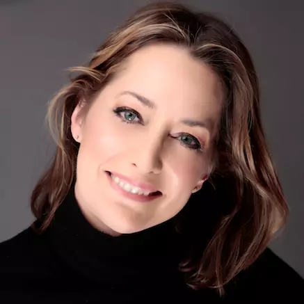 Karen has brown shoulder-length hair and smiling. She's wearing a black polo-neck top