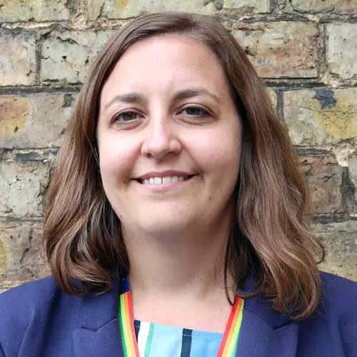 Woman with shoulder-length brown hair and brown eyes, smiling and wearing a dark blue jacket