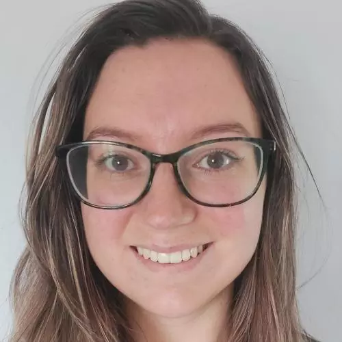 Tamara has long hair and is wearing dark glasses, smiling at the camera. 