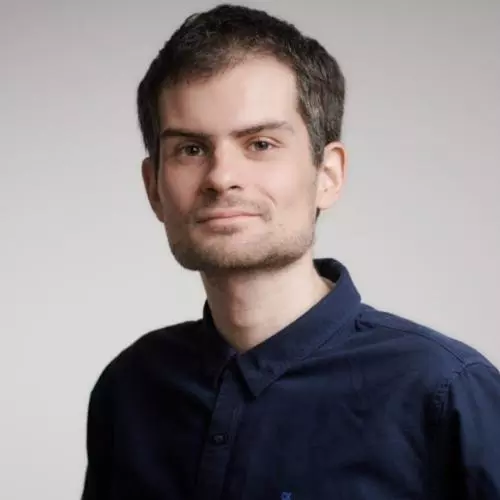 Kristijan Fidanovski has short brown hair and is wearing a navy blue shirt. 