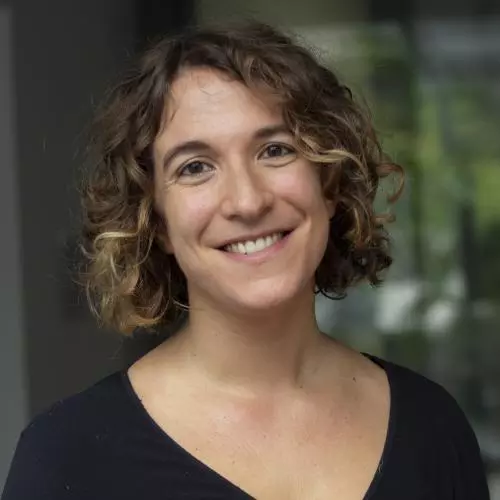 Arianna Tassinari and shoulder length brown hair and is smiling at the camera