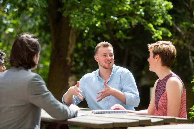 DSPI students having a discussion around a table in the garden at Barnett House